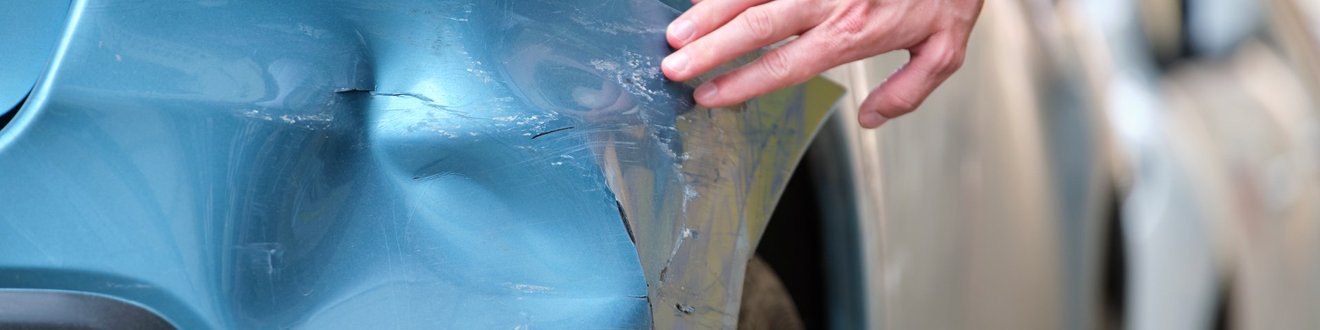Person running their hand across dent made on car