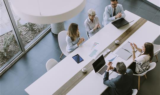 Business people around table with documents and laptops